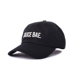 Angled view of black dad hat with white embroidered 'Sauce Bae' logo on the front. Perfect for fans of Sauce Bae, a health-focused hot sauce and raw honey brand.